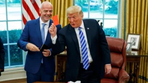 US President Donald Trump holds a red card alongside FIFA President Gianni Infantino during the Trump FIFA Review controversy involving Folarin Balogun.