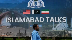 US Iran Talks banner in Islamabad featuring Pakistan, United States and Iran flags ahead of the upcoming technical negotiations.