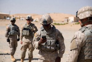 US soldiers in desert uniforms looking at a smartphone as concerns rise over US troops phones and operational security