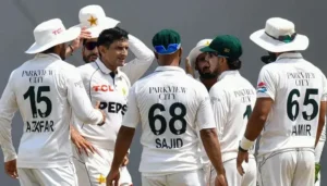 Pakistan cricket players in white kits gather in a team huddle on the field after West Indies win in the first Test