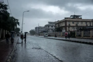 People walking with umbrellas on wet street during Karachi rain today under cloudy monsoon skies