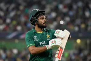Pakistan all-rounder Khushdil Shah in green jersey holding bat during a match after dismissing quitting Pakistan cricket rumours