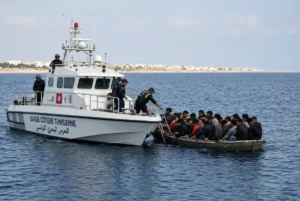 Tunisian coast guard boat rescuing migrants from a small vessel during the Tunisia boat disaster in the Mediterranean Sea