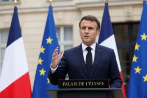 Emmanuel Macron gesturing while speaking at the Elysee Palace podium during Macron Yanbu port announcement