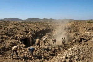Miners and rescuers carefully clearing rubble from collapsed shafts at a Sudan gold mine site in West Kordofan under clear blue sky