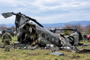 Italian military helicopter wreckage at the Bosnia helicopter crash site with soldiers and emergency responders.