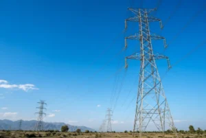 High voltage electricity transmission pylons and power lines under clear blue sky related to higher electricity charges reforms