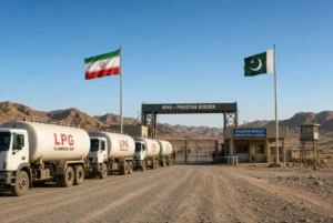Iran Pakistan border crossing with LPG tanker trucks waiting for clearance, Iranian and Pakistani flags flying under clear blue sky